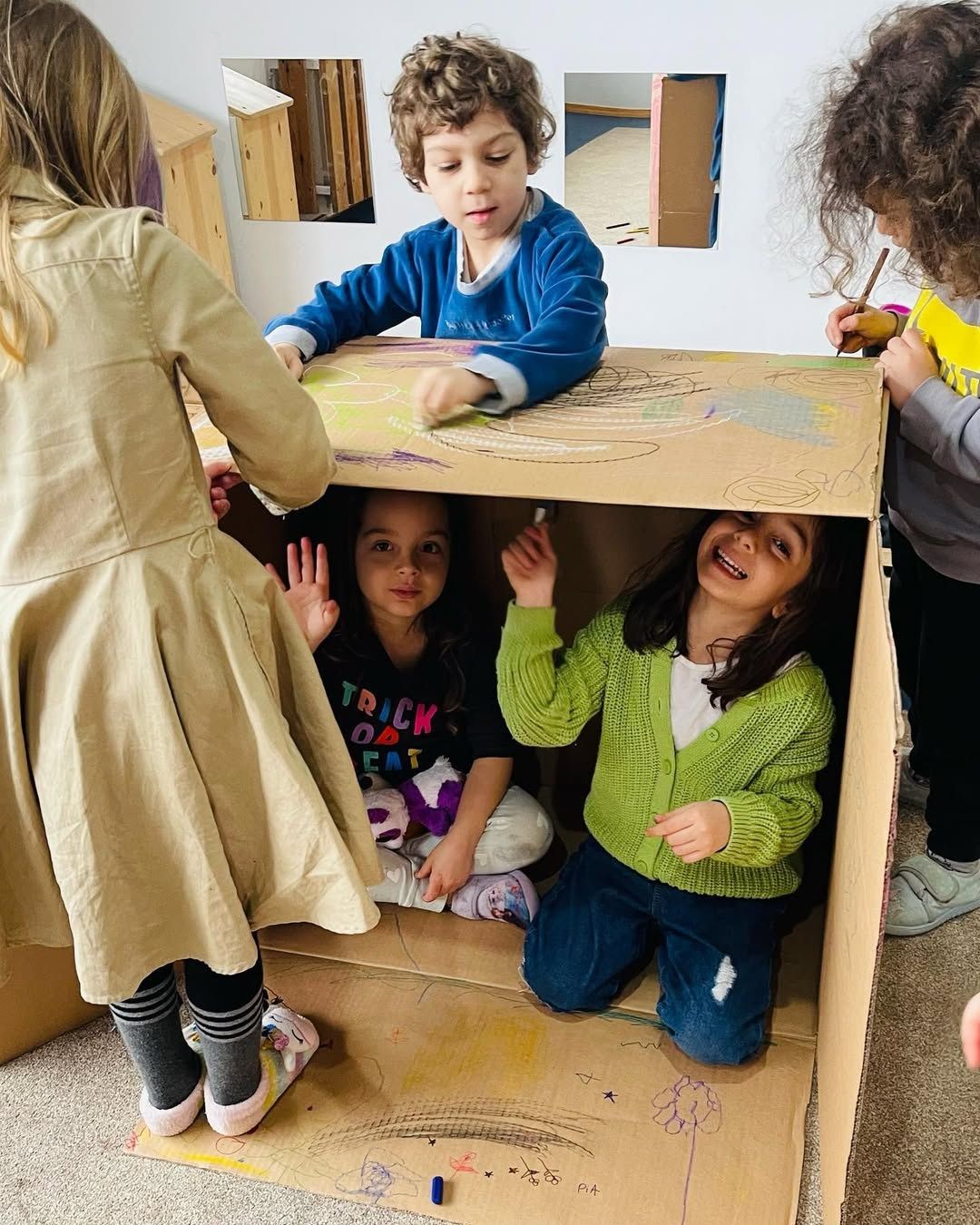 Karton kutudan yaptıkları oyun evinin içinde ve çevresinde çocuklar